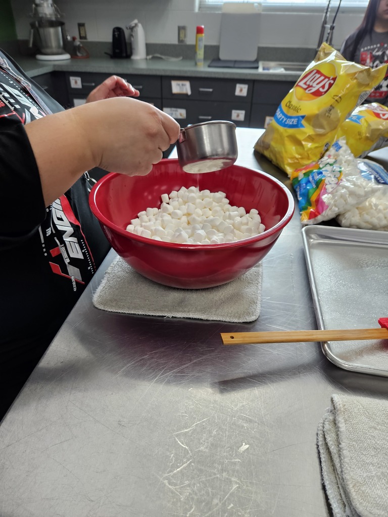 student pouring something over a bowl of mini marshmallows